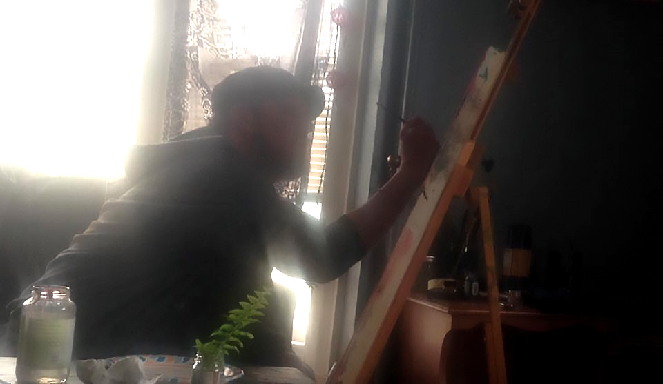Nat Jefferson sitting infront of his easel and painting.